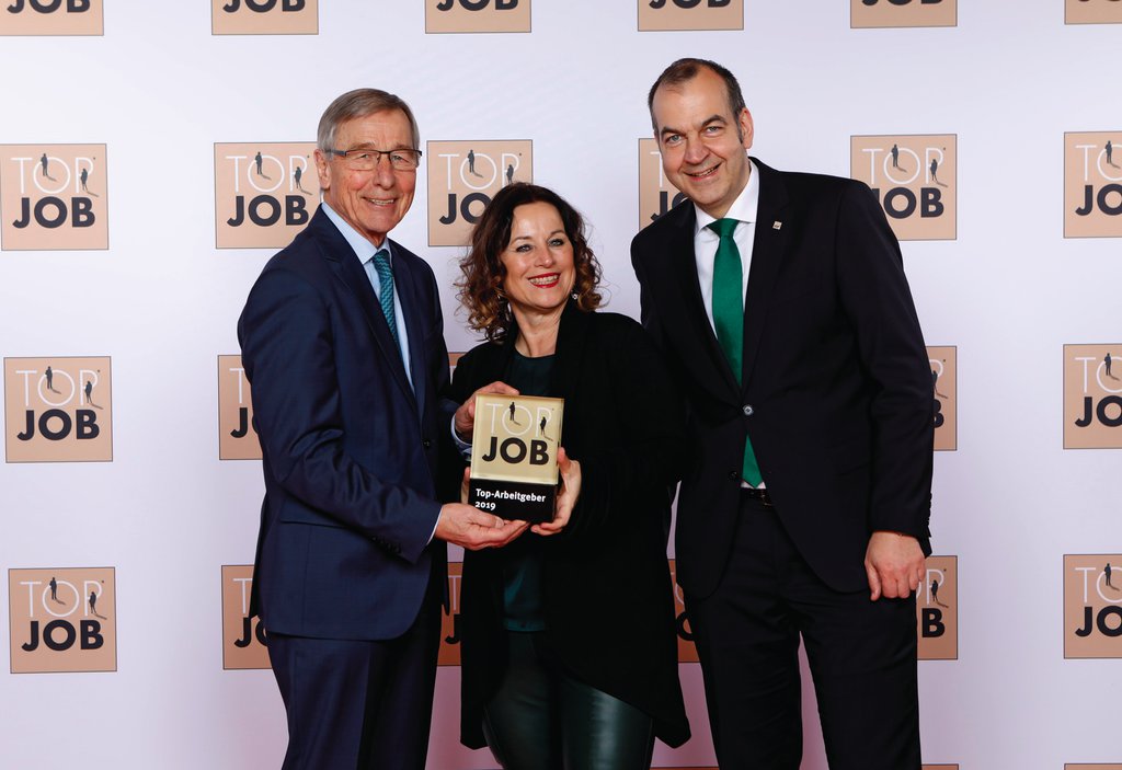 Zwei Männer und eine Frau halten einen Award mit der Aufschrift "Top Arbeitgeber 2019" in die Kamera.