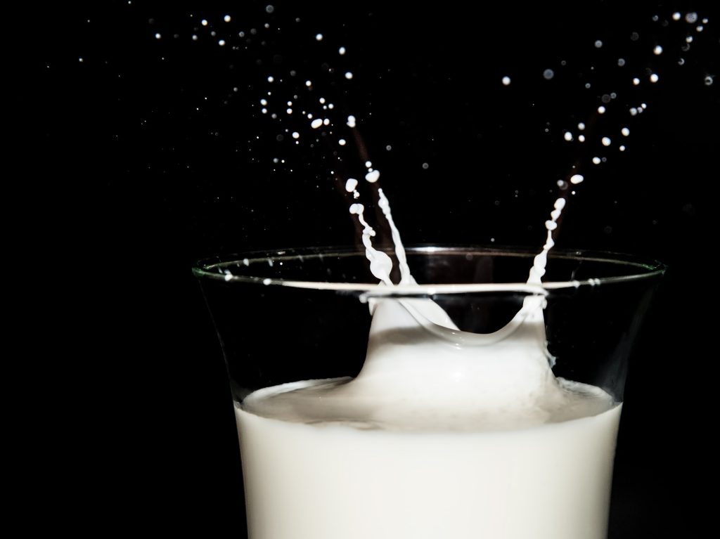Milchtropfen spritzen aus einem Glas Milch.